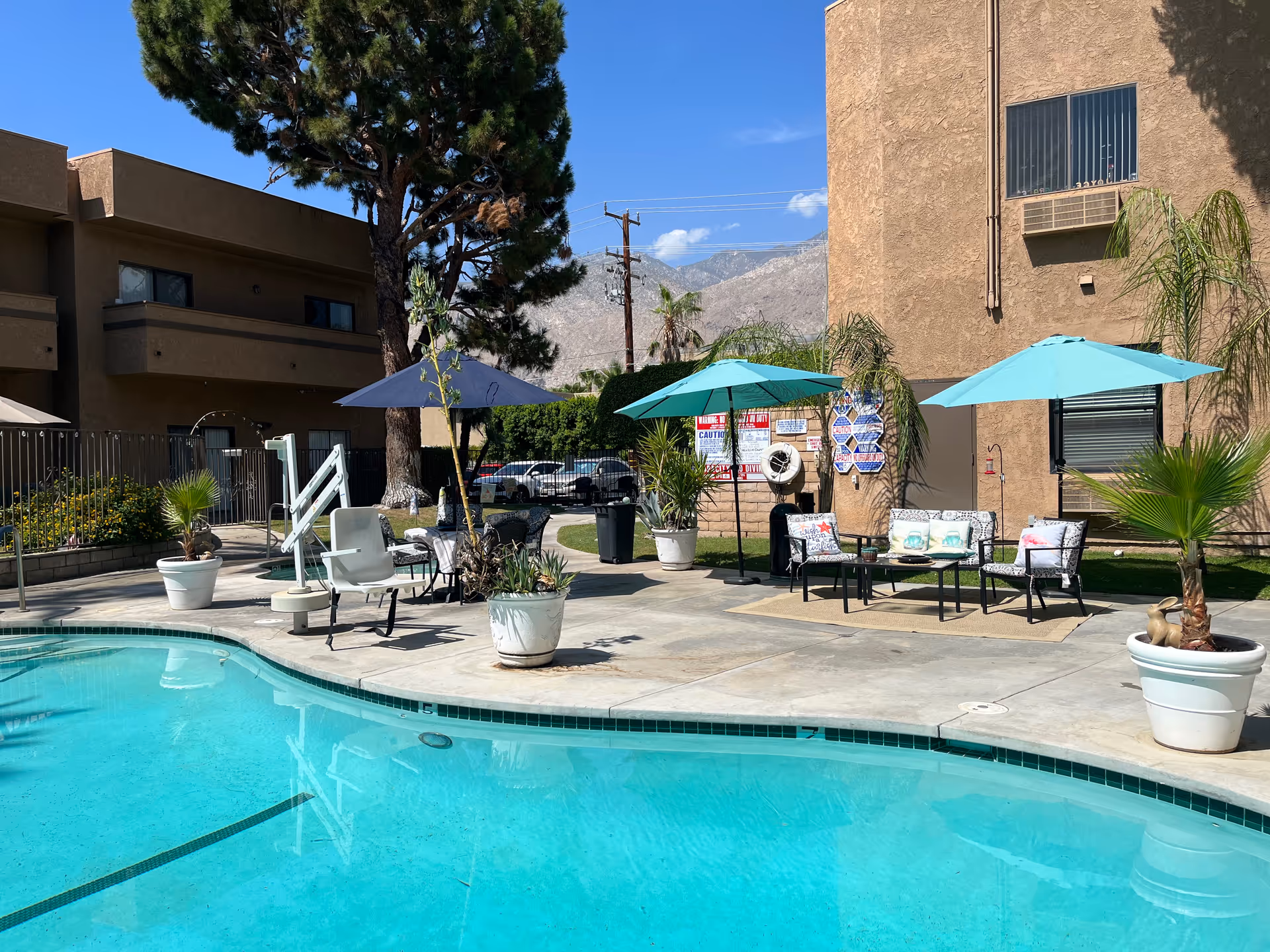 Outdoor pool area at Windsor Court Assisted Living with seating and umbrellas.