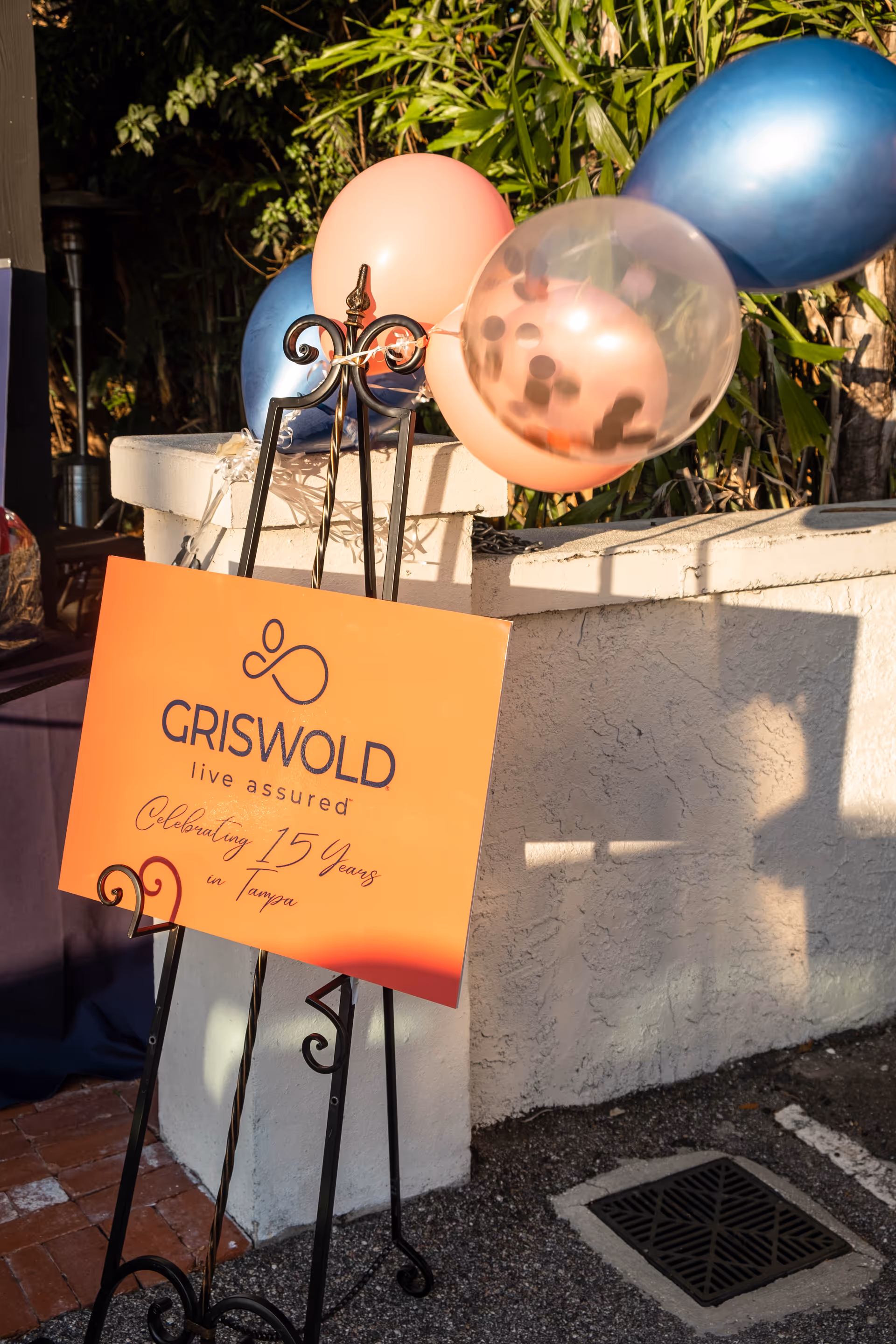 Griswold sign with balloons celebrating 15 years beside a white exterior wall