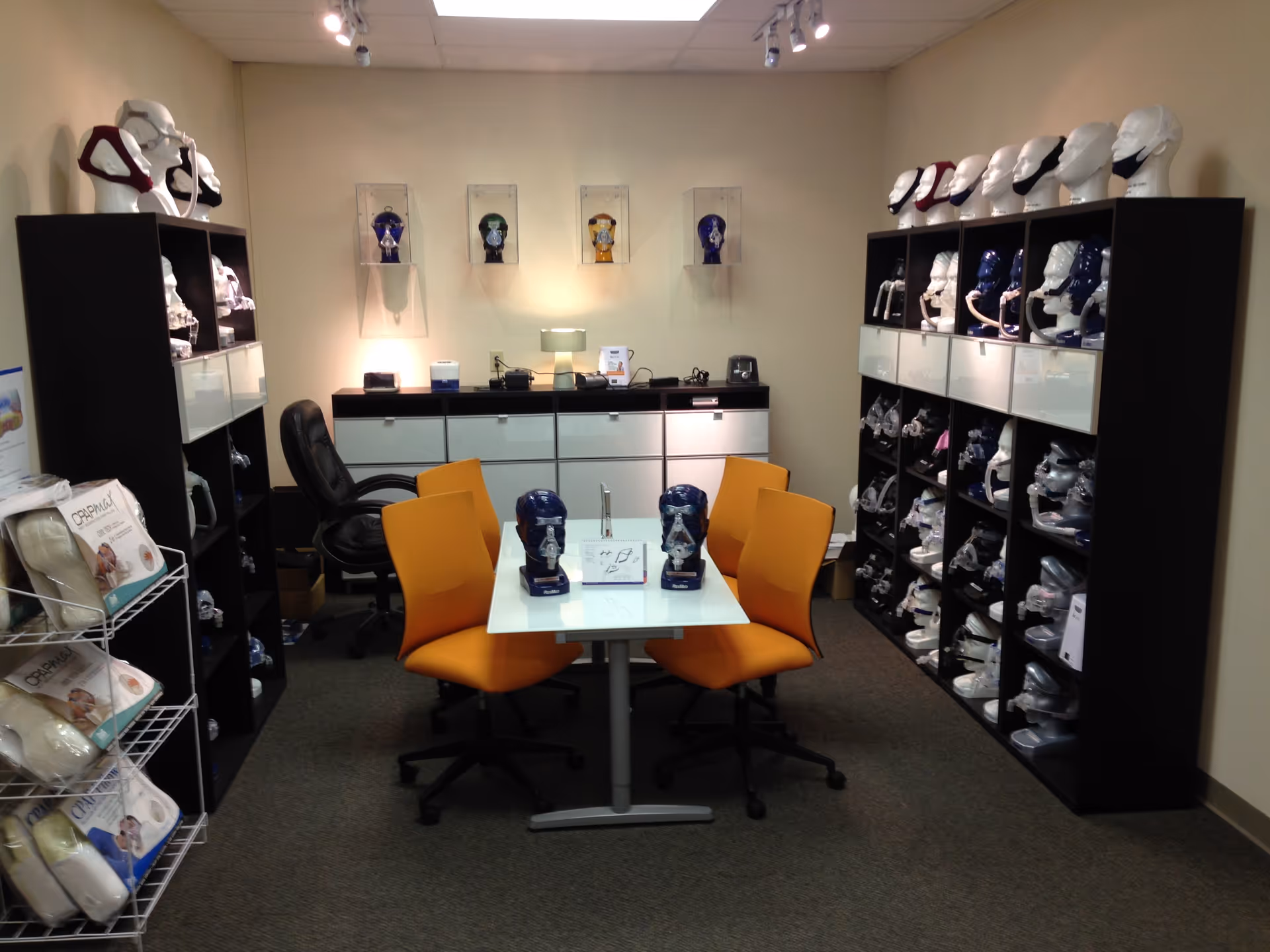 Interior showroom with orange chairs, a glass table, and shelves of orthotics.