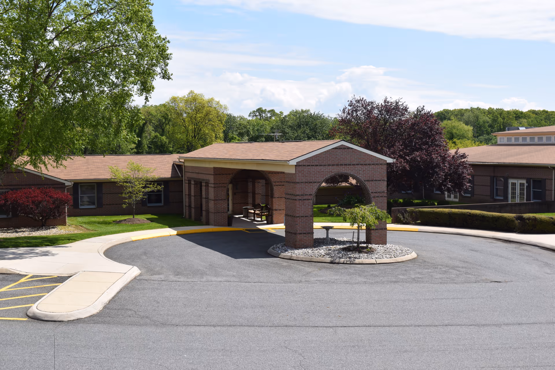 Brick facility with a covered circular driveway and landscaped entrance.