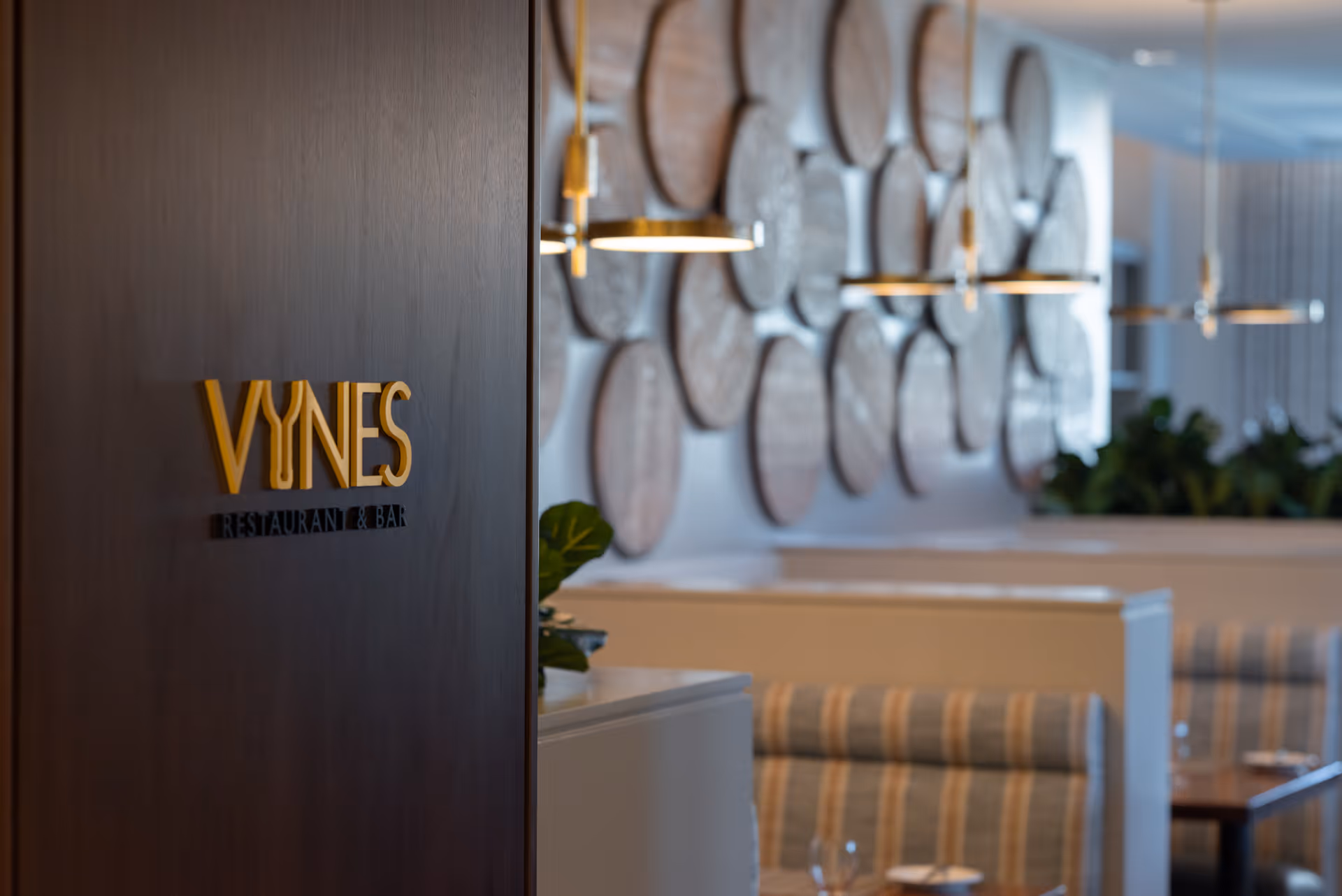 Wood-paneled wall sign reads 'VINES RESTAURANT & BAR' beside dining booths.