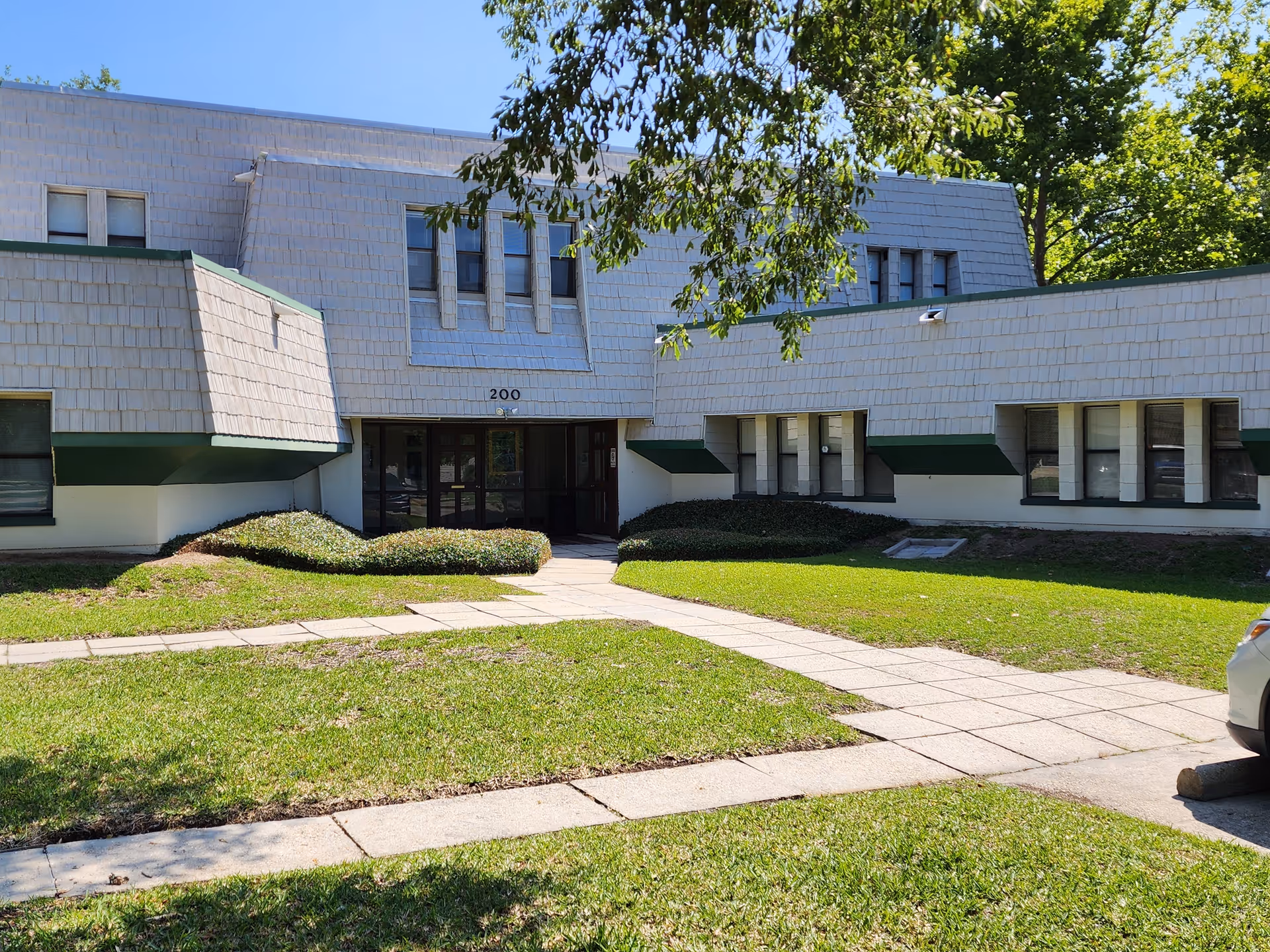 Front view of a low, modern senior living building with a grassy lawn and walkway.