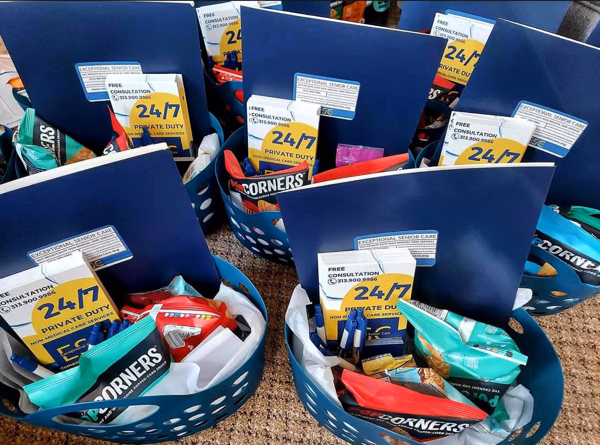 Blue baskets hold brochures labeled Exceptional Senior Care and snacks on a carpeted floor.