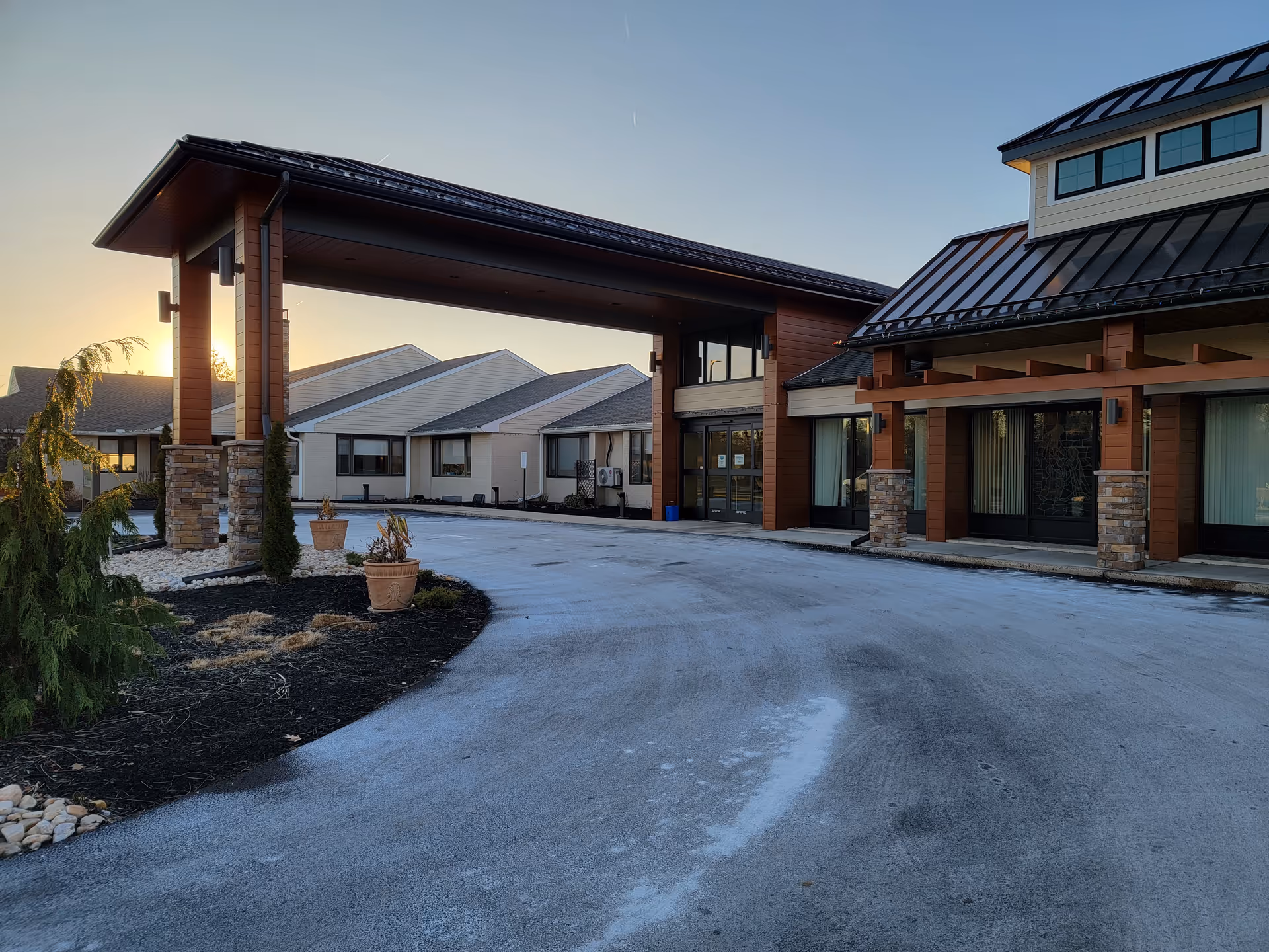 Front exterior of a senior living campus with a covered entrance and stone pillars.