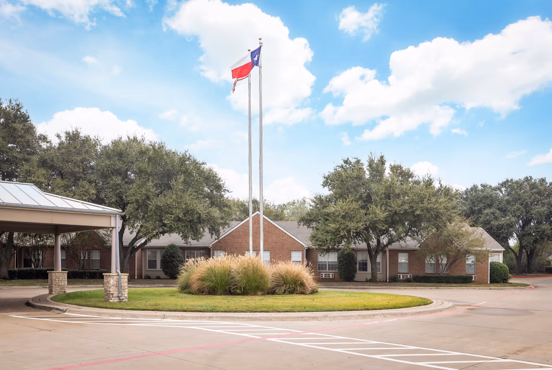 Front view of The Waterford on Cooper exterior with flagpoles and circular driveway.