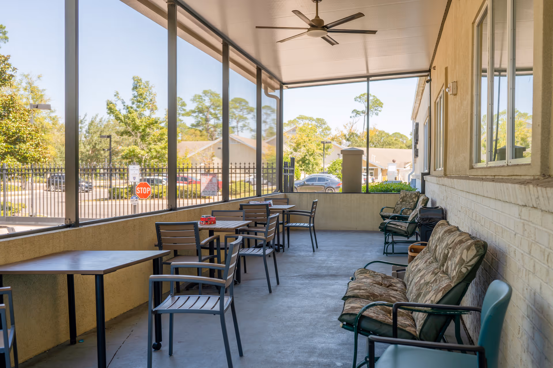 Covered outdoor patio with tables, chairs, and lounge seating beside a brick building.