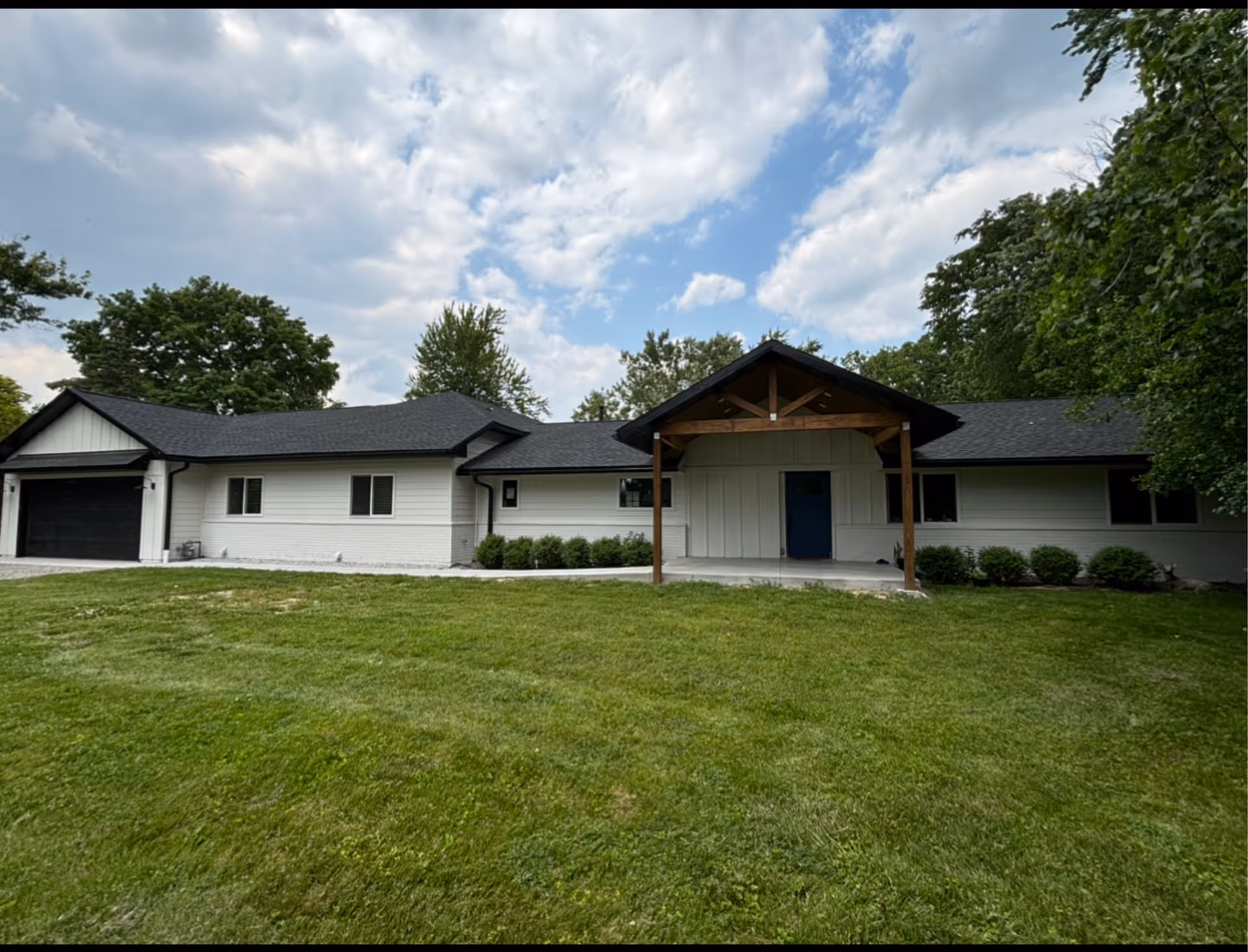 Single-story white building with dark roof, blue entry door, and expansive green lawn.