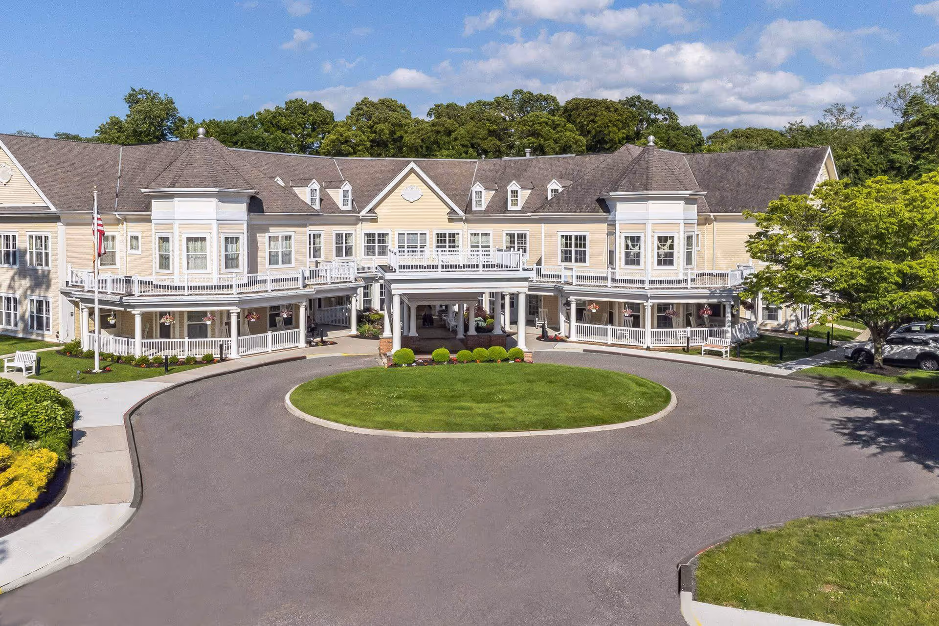Sunrise of East Setauket exterior view of a cream-colored senior living facility with a circular driveway.