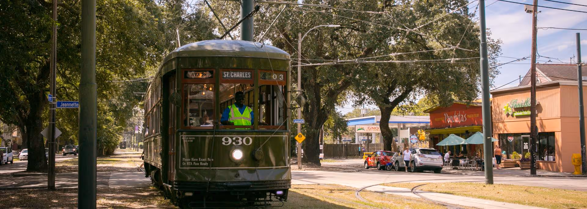 A vintage streetcar with a worker in a neon vest on tracks.