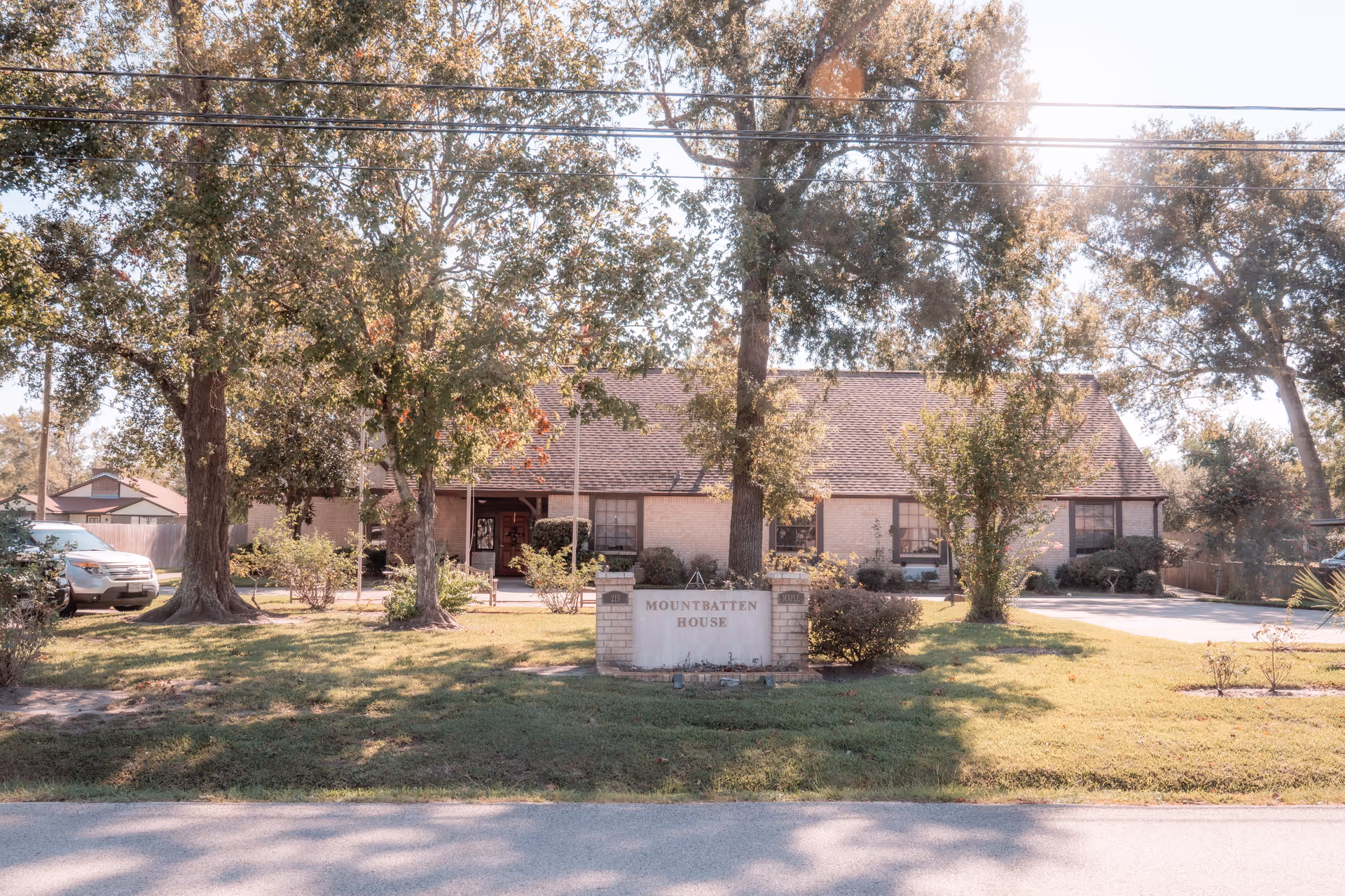 Front exterior of a single-story brick building with a lawn and a sign reading 'Mountbatten House'.