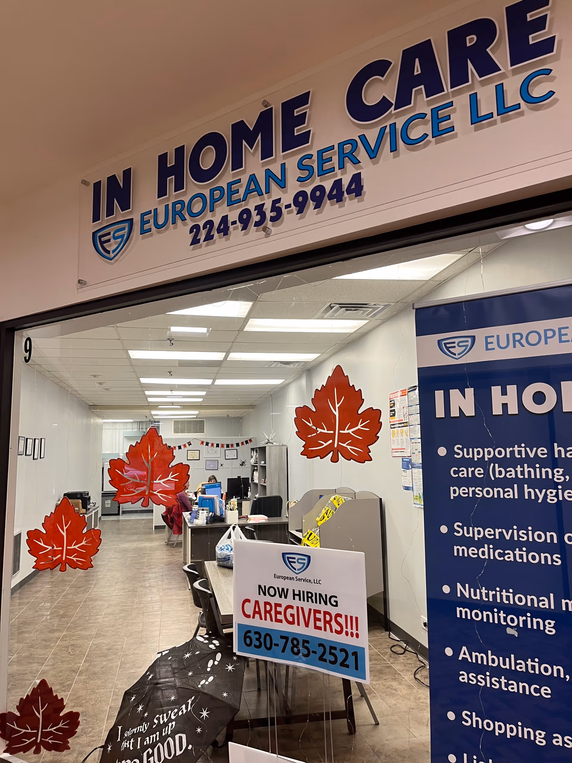 Interior reception area of European Service LLC In Home Care, featuring desks and red leaves.