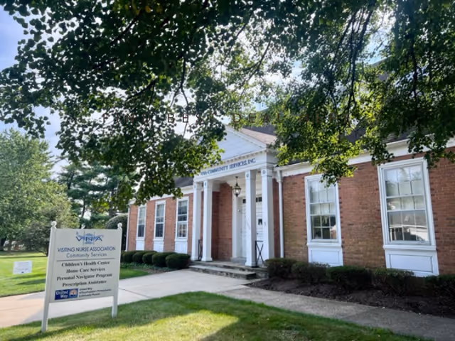 Brick building with white columns and a front entrance, signage for Visiting Nurse Association.