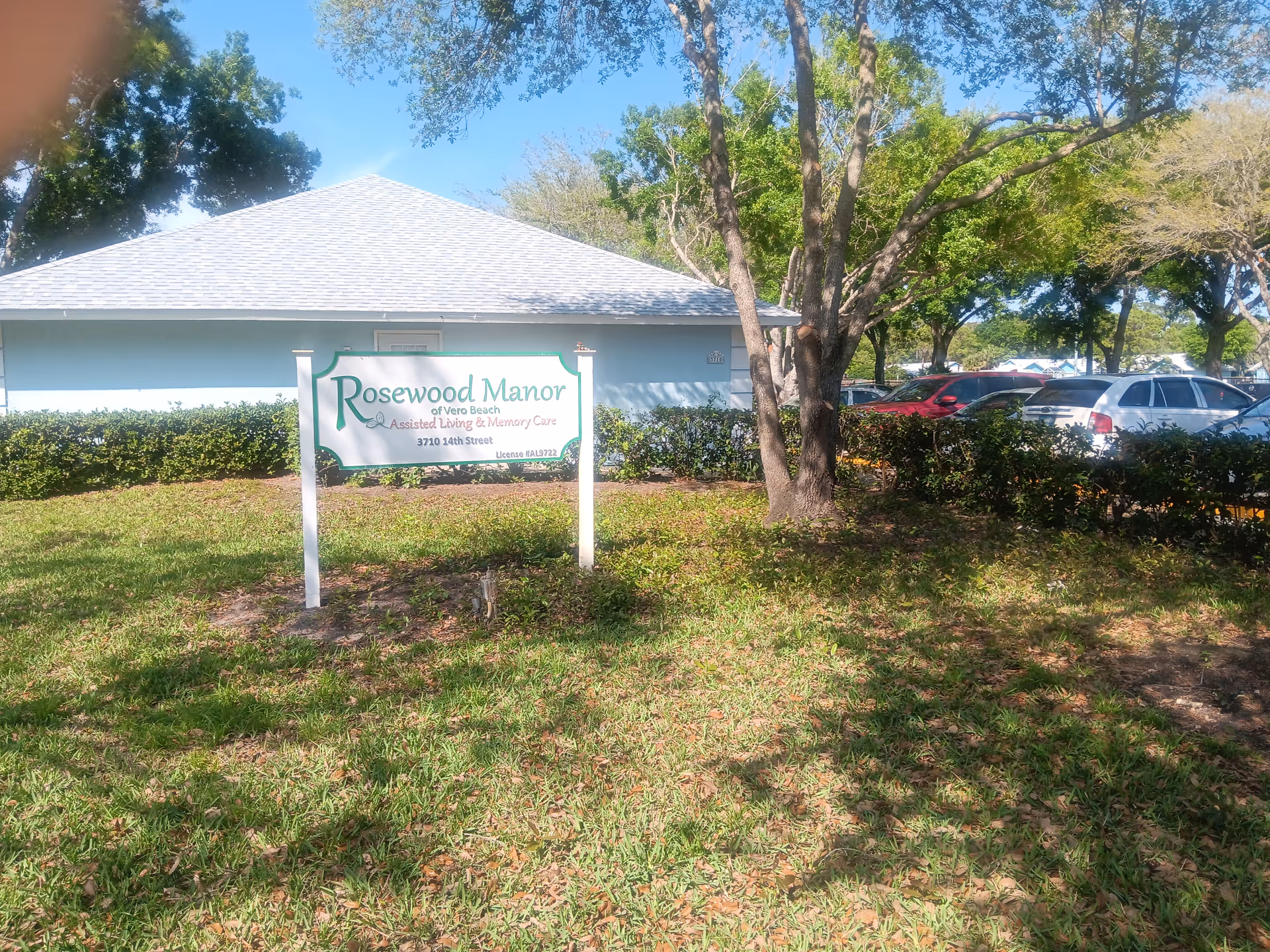 Exterior view of Rosewood Manor of Vero Beach with sign and parking
