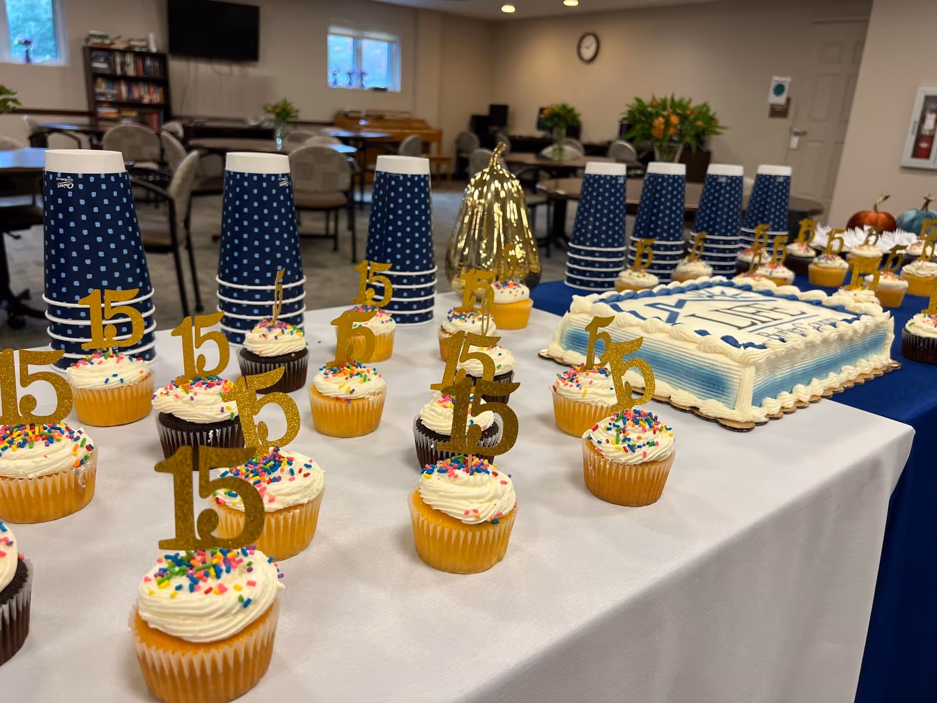 Indoor dining area with cupcakes, a birthday cake, and blue polka-dot cups.