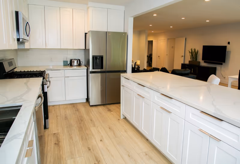 Bright modern kitchen with white cabinets, stainless appliances, and a large island.