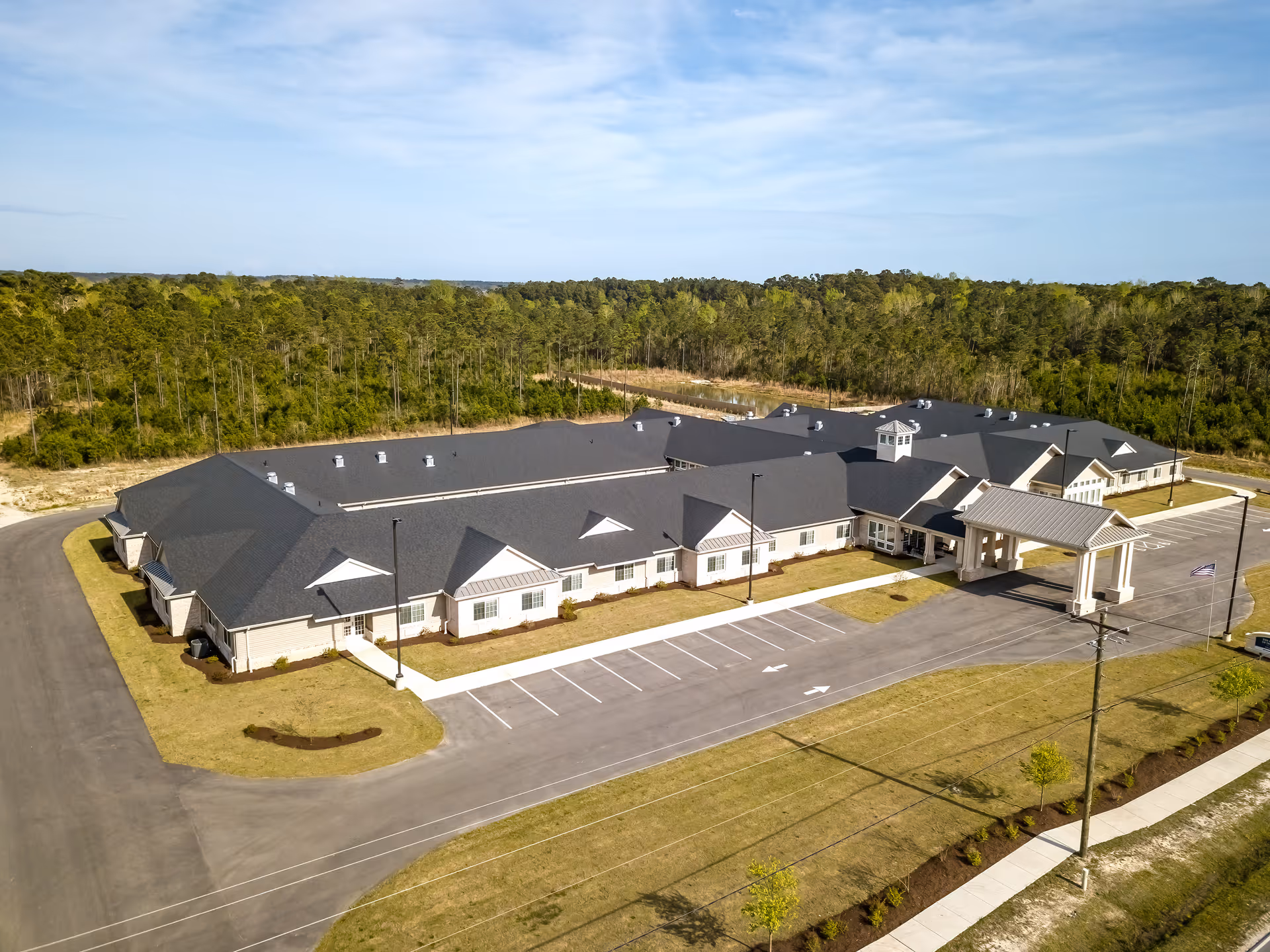 Aerial view of The Landings of Swansboro senior living facility with parking and surrounding woods