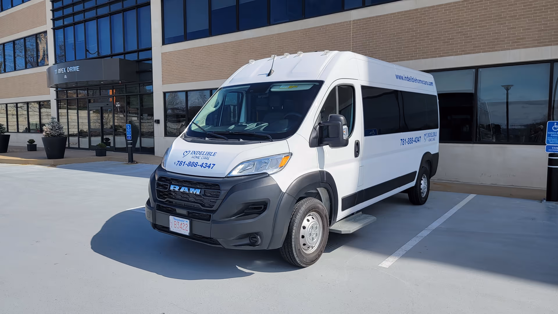 White Indelible Home Care van parked in front of a glass-front building.