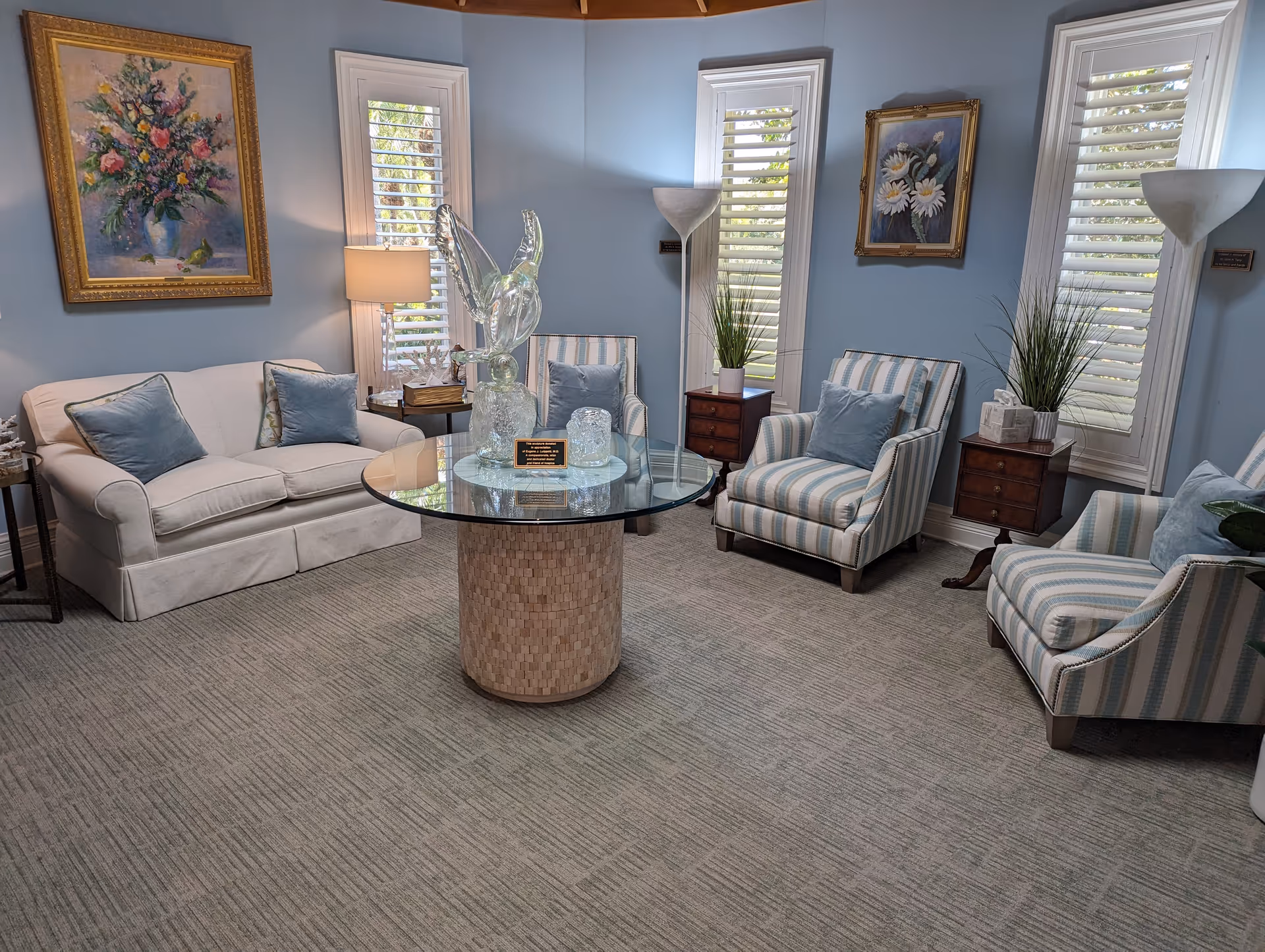 Pastel-blue living room lounge with striped chairs, sofa, and glass coffee table.