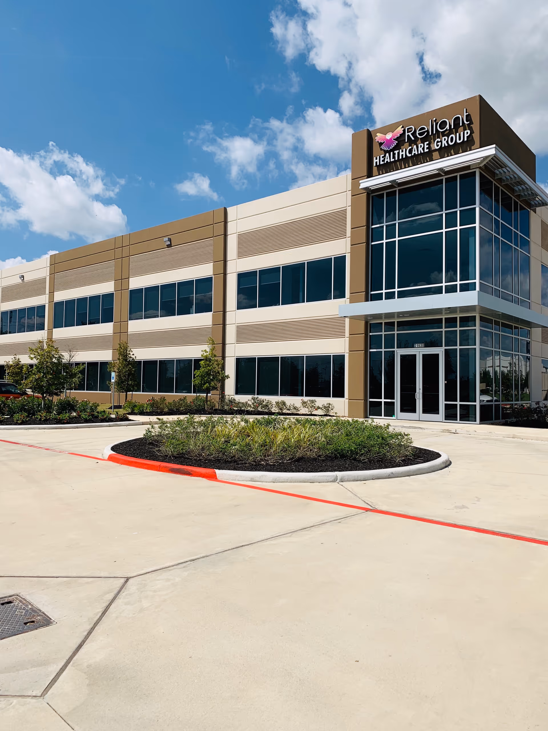 Exterior view of a Reliant Healthcare building with glass frontage and landscaped circular driveway.
