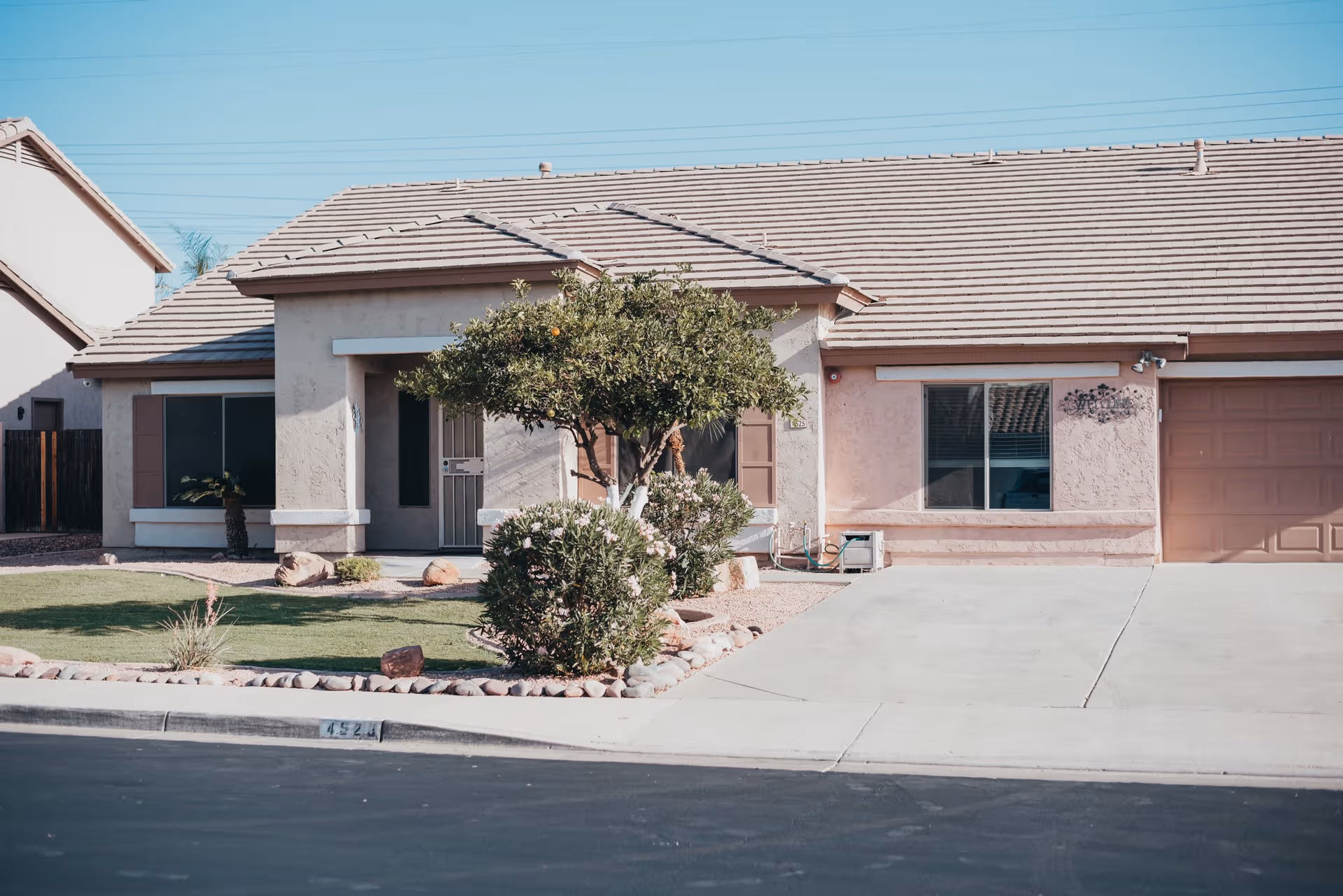 Single-story building front with front yard, driveway, and desert landscaping.