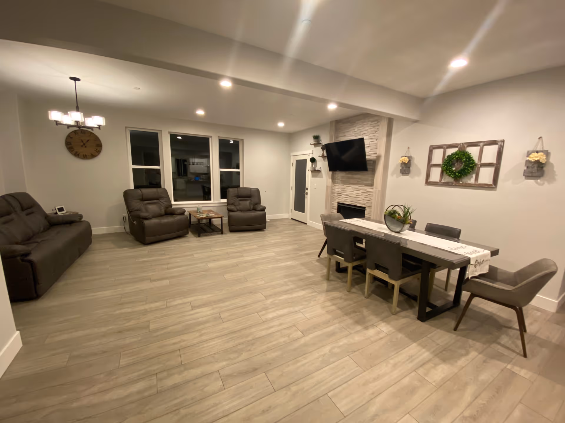 Spacious senior living common area with recliners, dining table, TV, and fireplace.