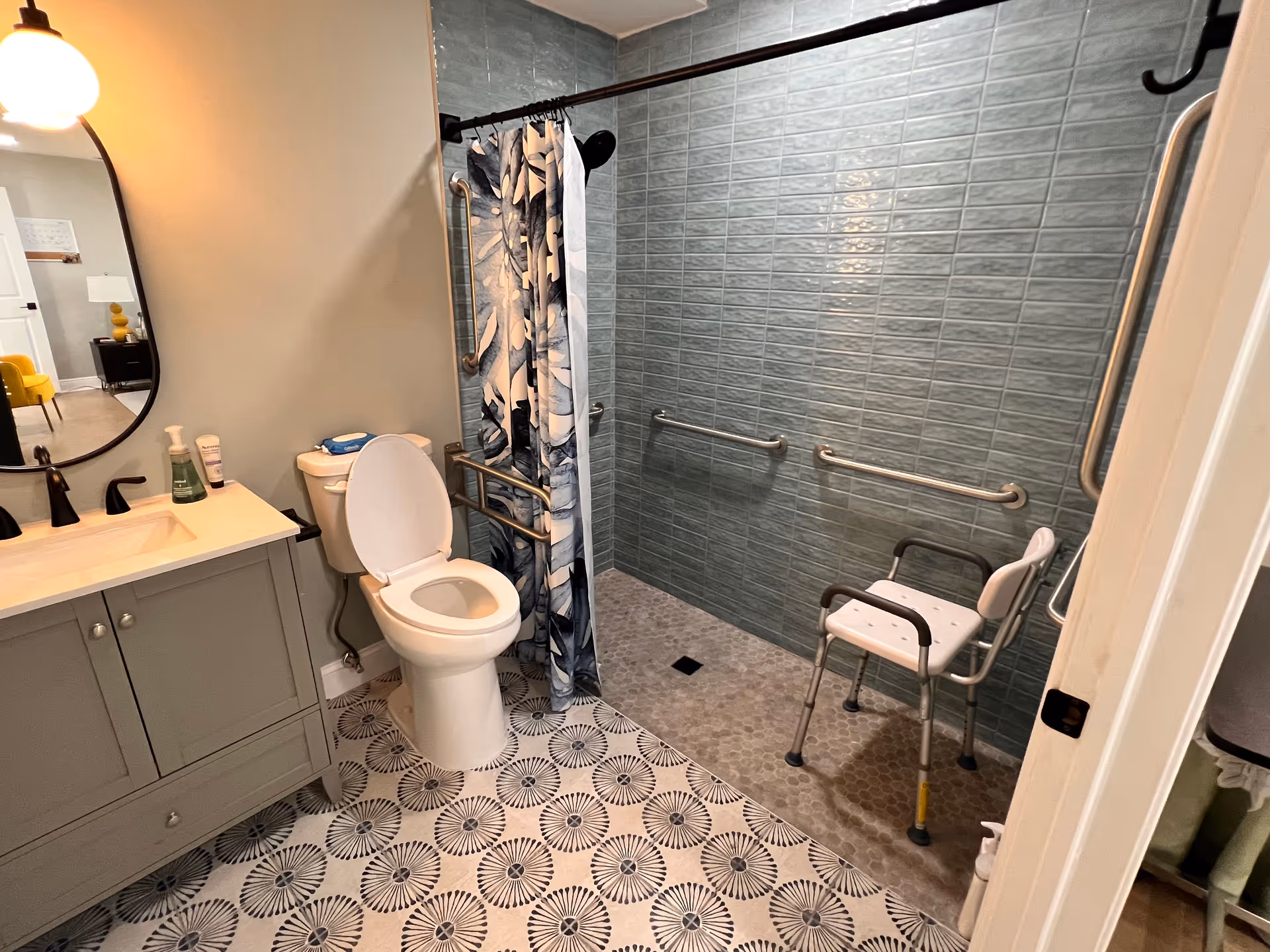 Accessible bathroom with sink, toilet, shower, grab bars, and a shower chair.