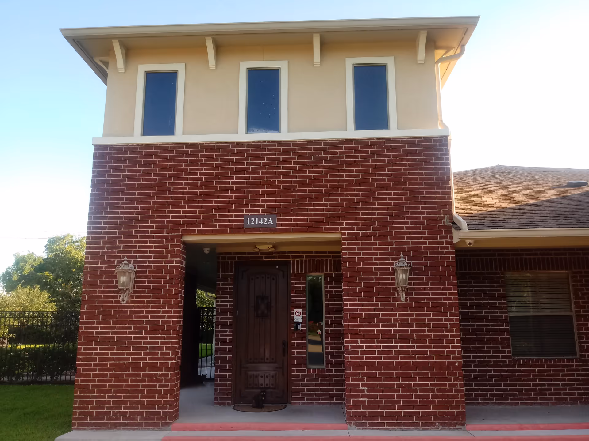 Brick senior living facility facade with a tall entryway and three upper windows.