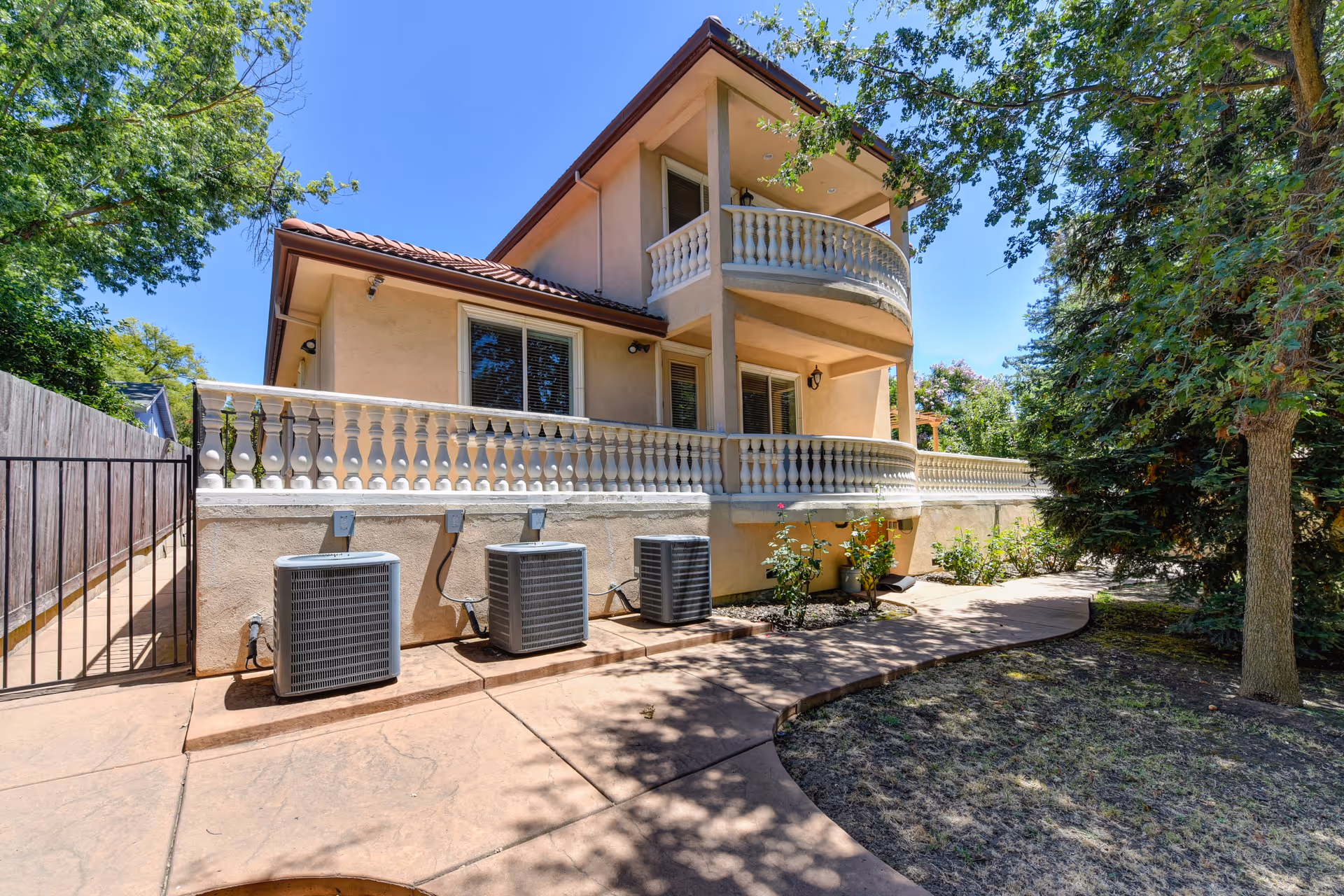 Two-story beige senior living building with balconies, air conditioning units, and a paved walkway.