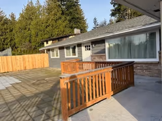 Single-story building with a wooden railing deck and wide concrete patio.