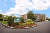 Exterior view of a senior care facility with sign, landscaping, and a parking lot.