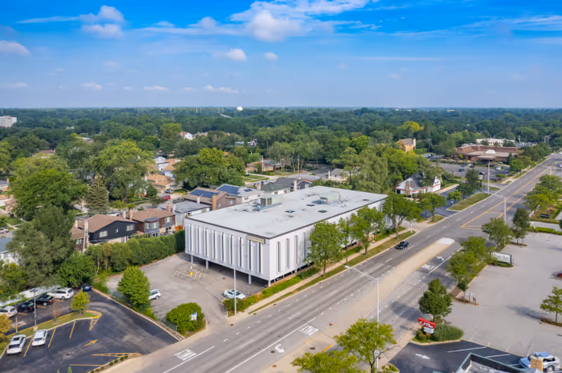 Aerial view of a white modern senior living facility beside a busy street.