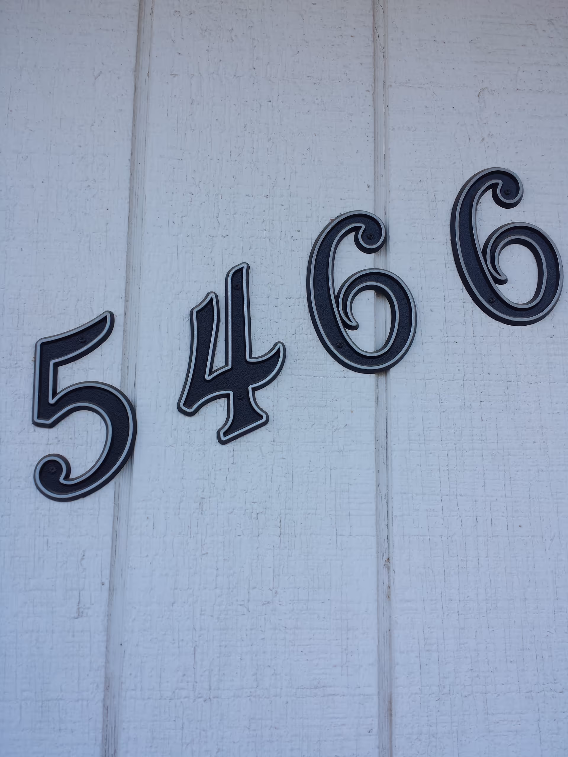 Close-up of white exterior wall with house numbers 5466.