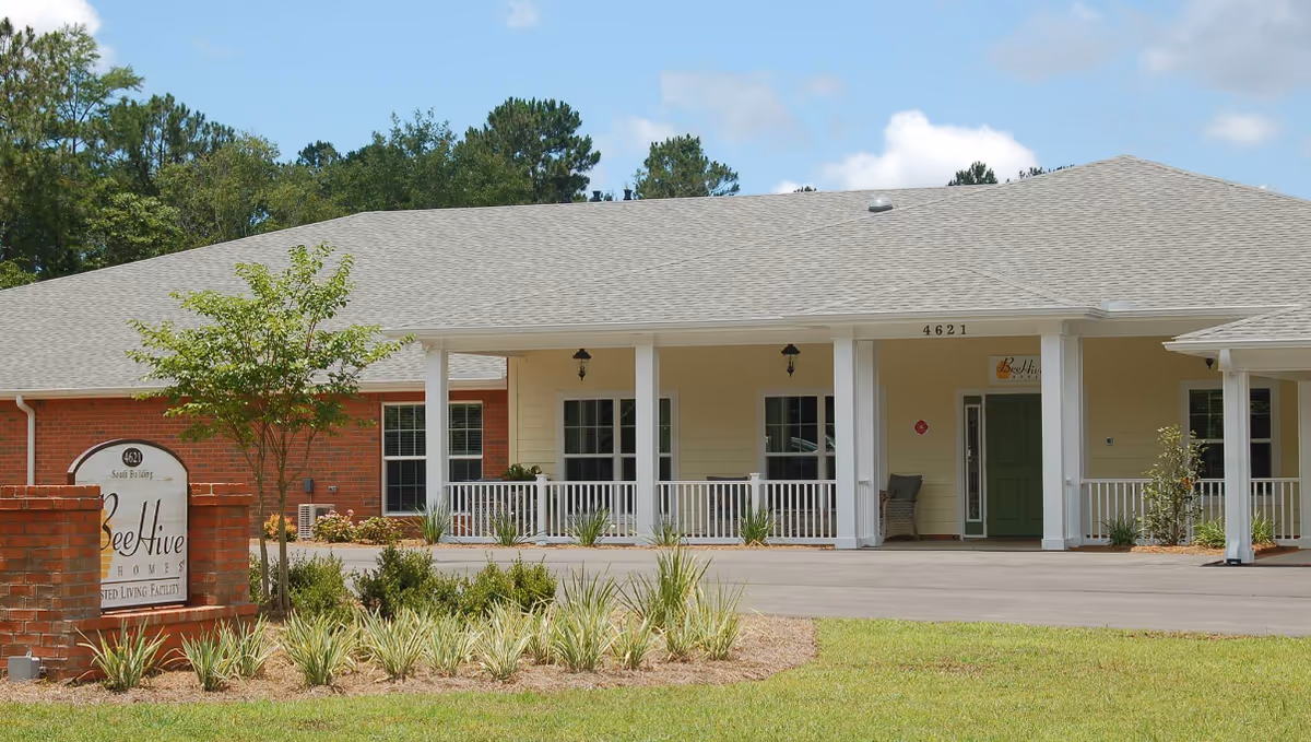 Front exterior of Grove Street Group Home featuring a covered porch, columns, and landscaped surroundings.