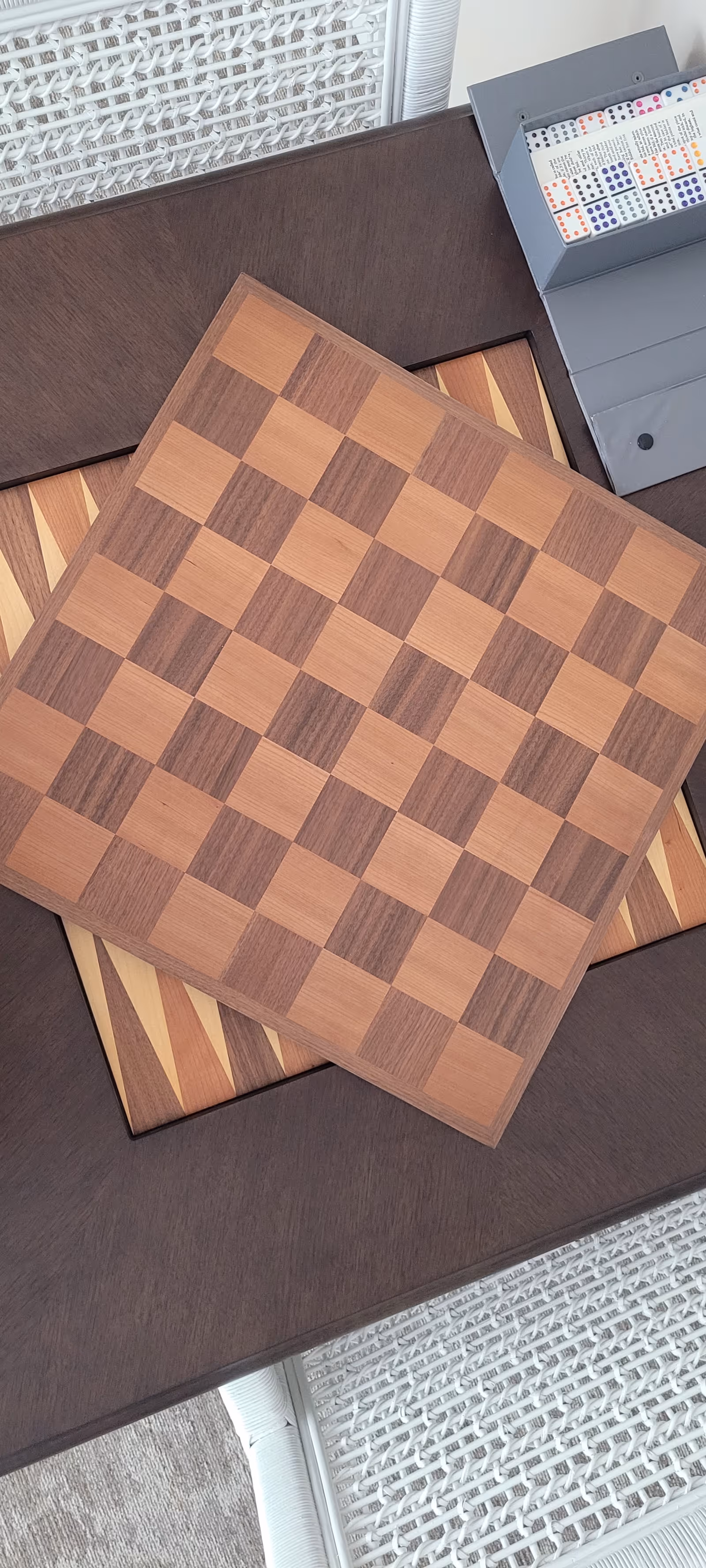 Two wooden checkerboards stacked on a dark table with a woven rug nearby.