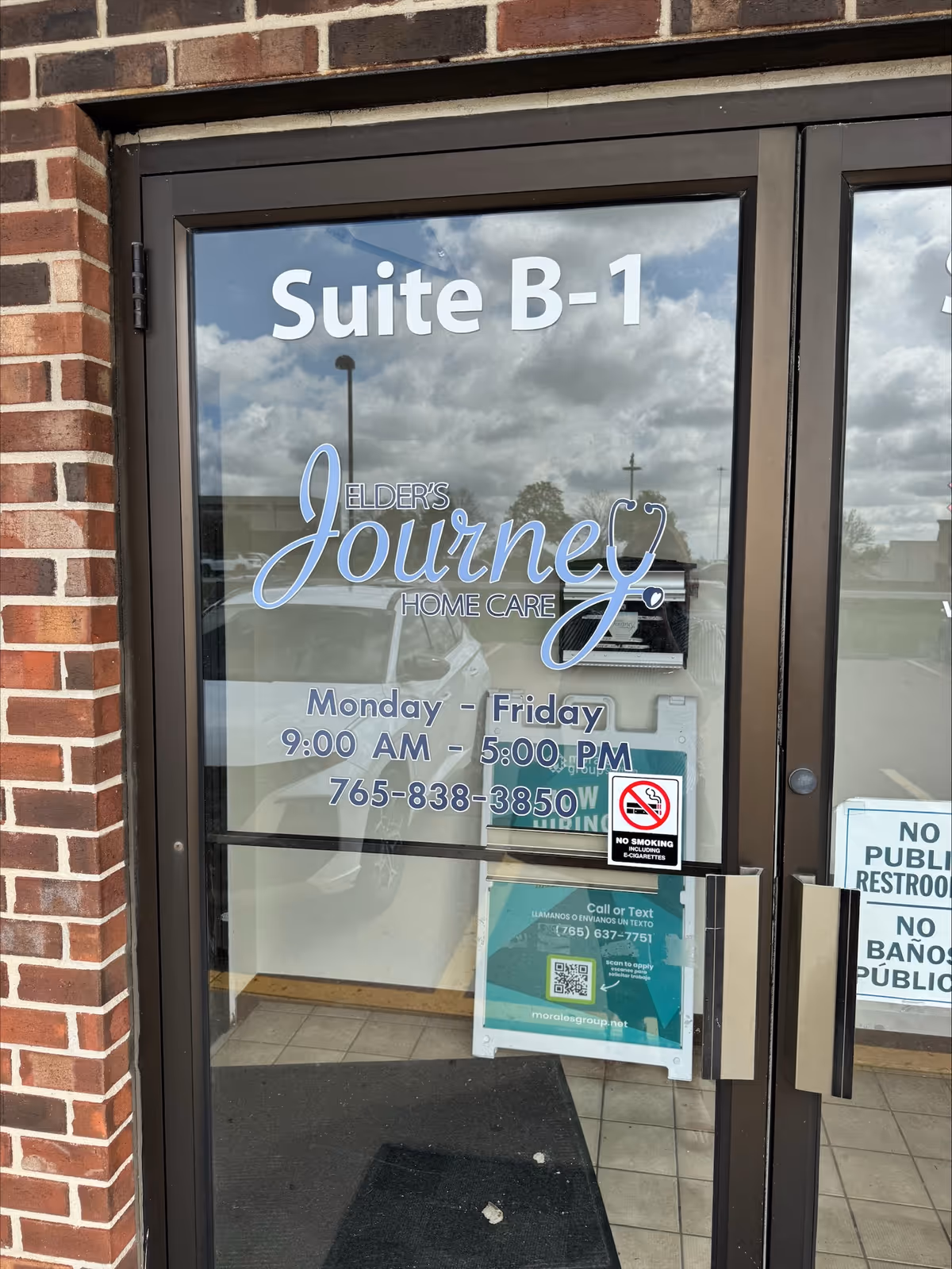 Glass door of a brick building labeled Suite B-1 for Elder's Journey Home Care.