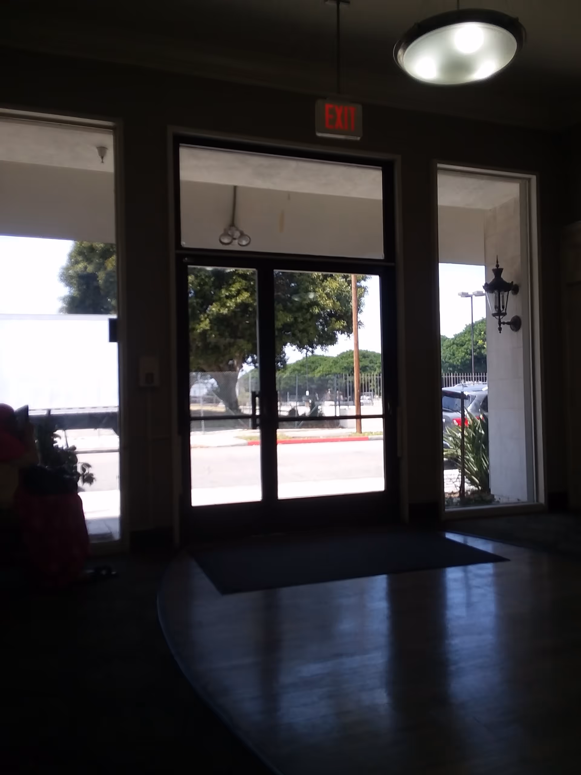 Interior lobby with glass doors, exit sign, and view of outdoors.