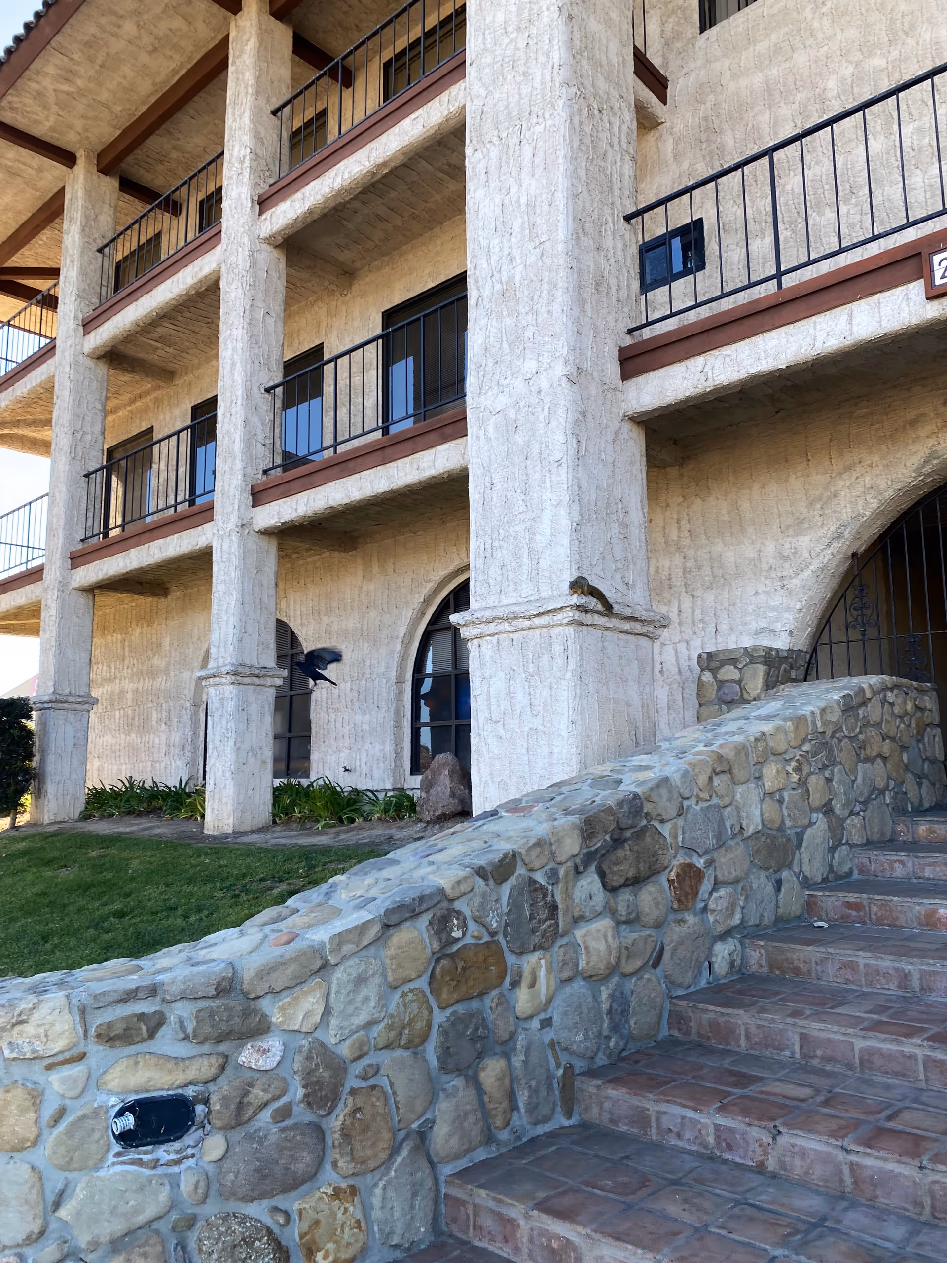 Stone-walled, multi-level exterior of a senior facility with balconies and stone stairs.
