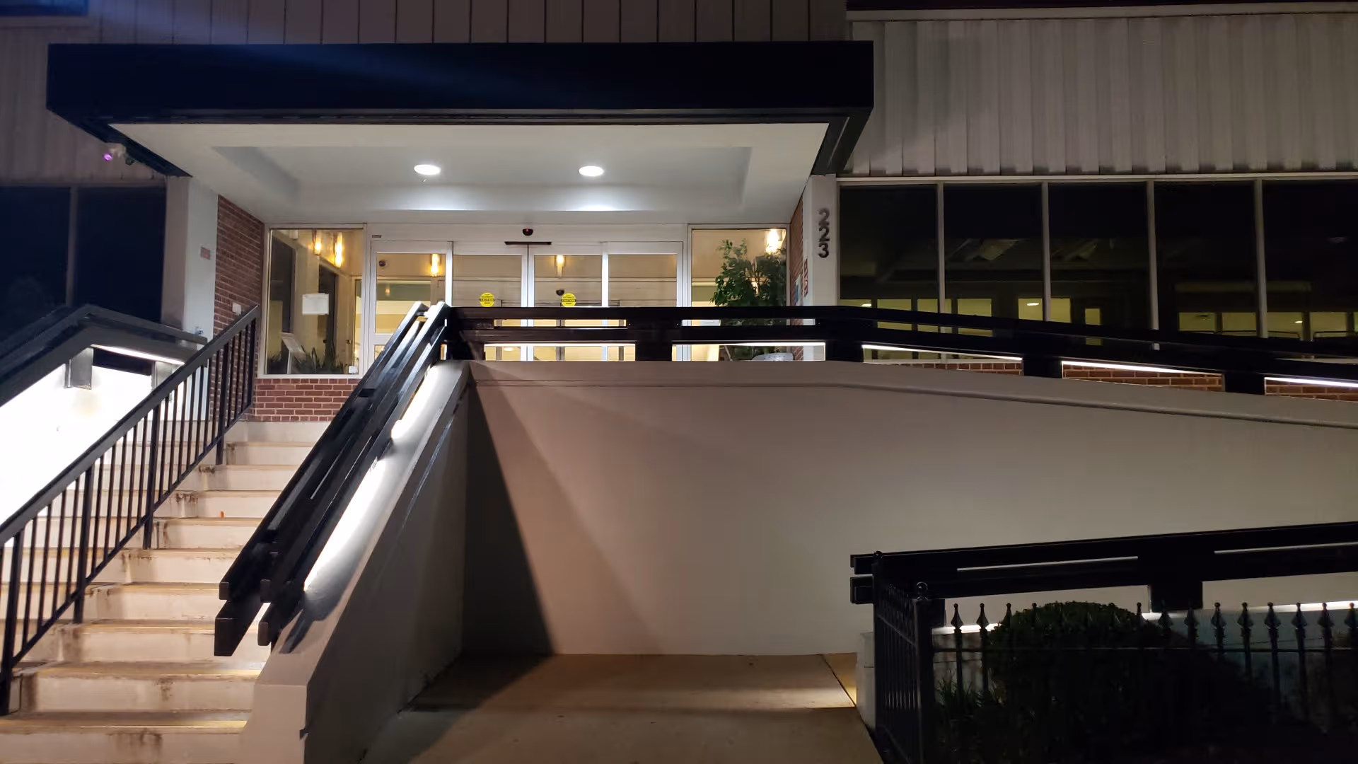 Night exterior of BridgePoint Hospital Capitol Hill entrance with stairs, ramp, and glass doors.