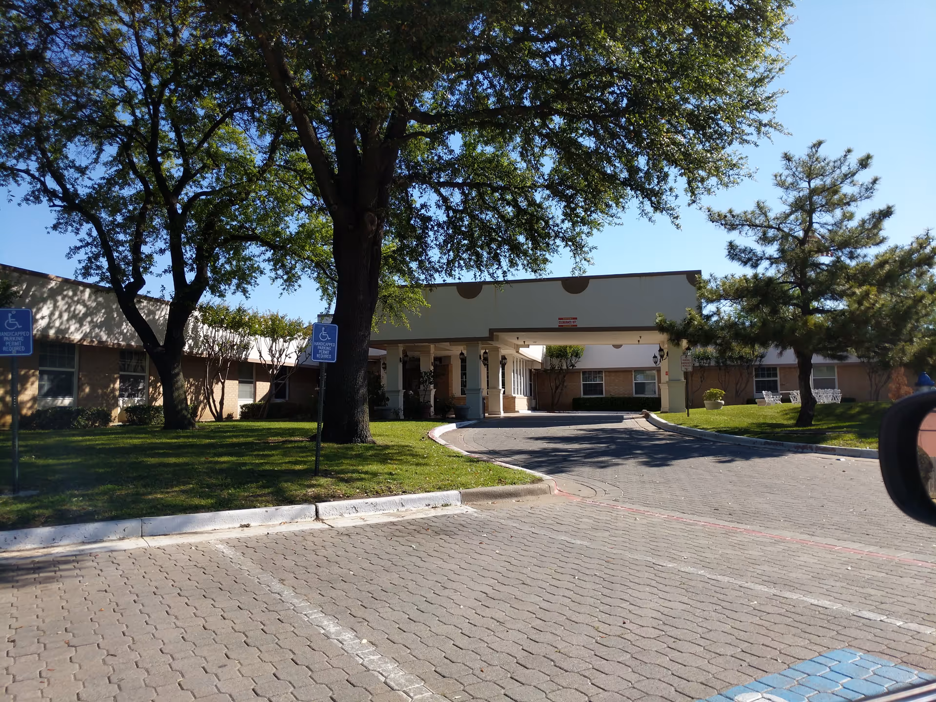 Front view of Highlands Guest Care Center with drive-up entrance and trees.