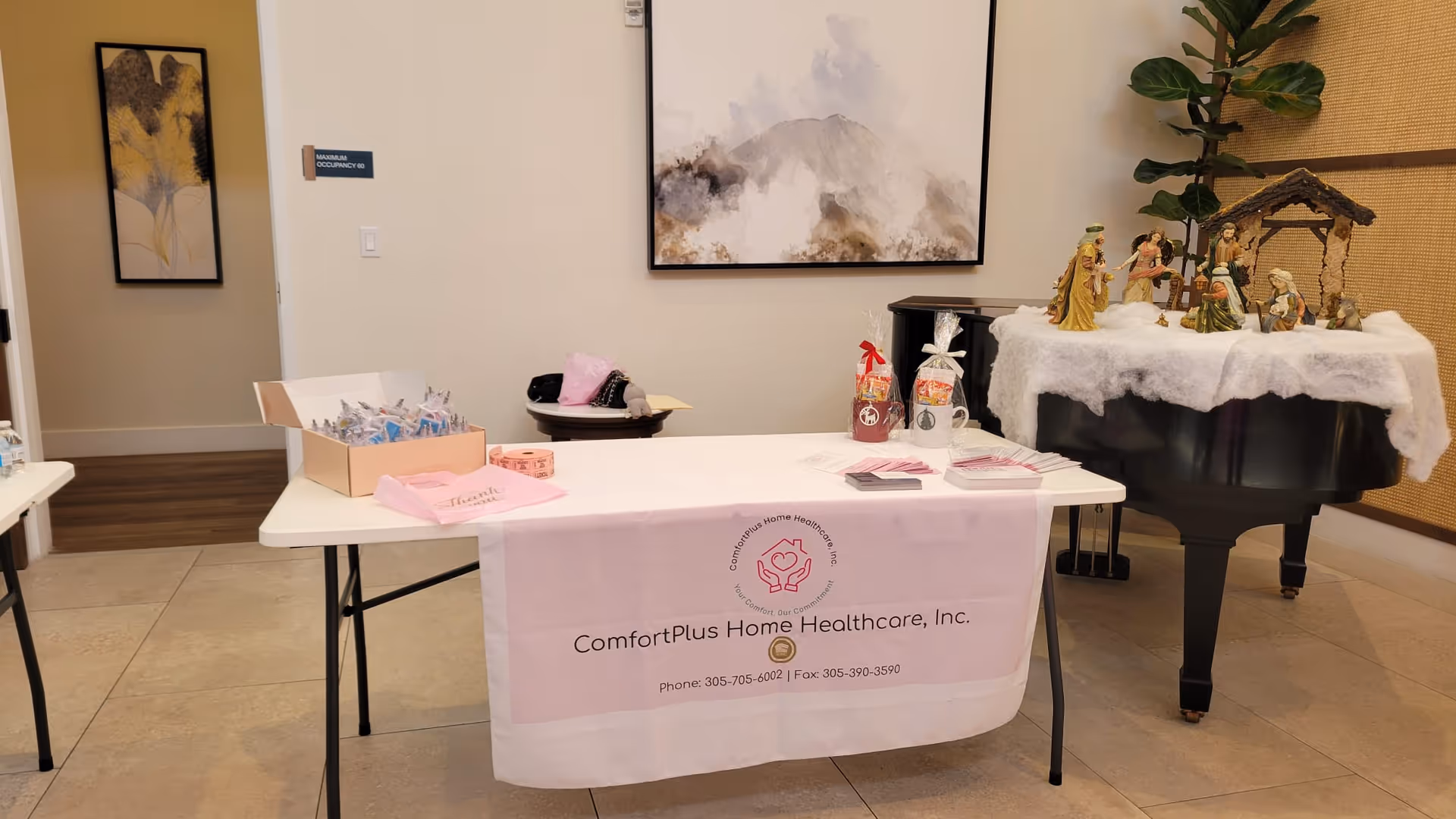 Reception area with a pink ComfortPlus banner on a table and nativity display.