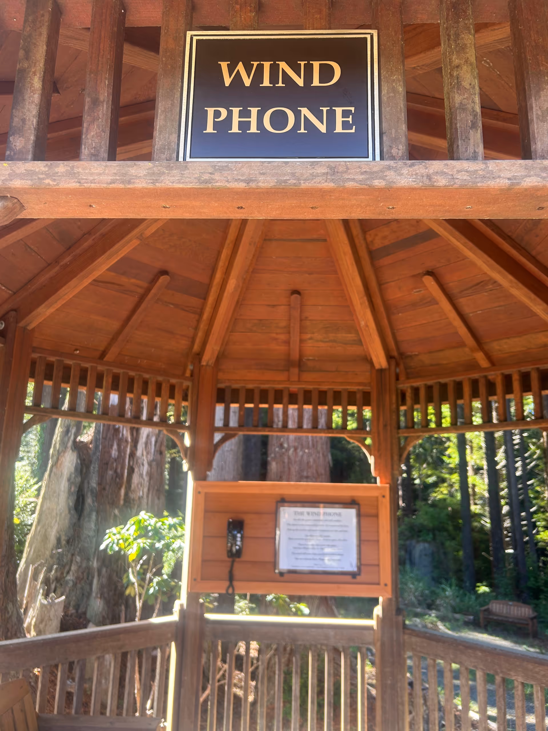 Wooden gazebo exterior featuring a wind phone sign and a wall-mounted phone.