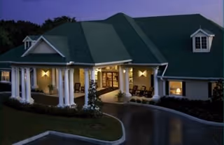 Exterior view of a senior living facility with a covered front entrance and columns.