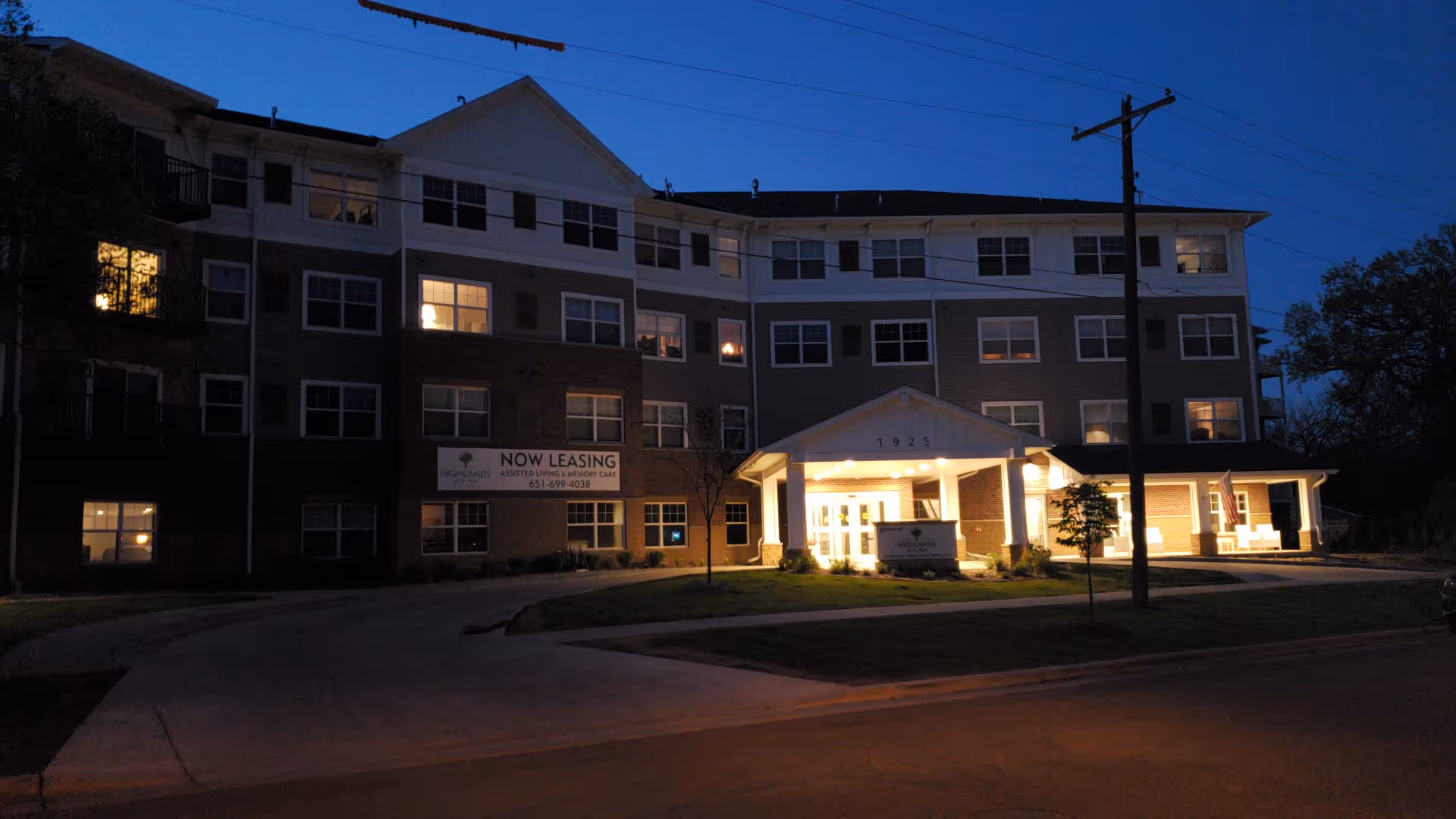 Night exterior view of Highland Path senior living building with illuminated entrance and signage