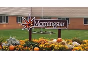 Exterior view of Morningstar Residential Care Center with a sign and autumn flowers.