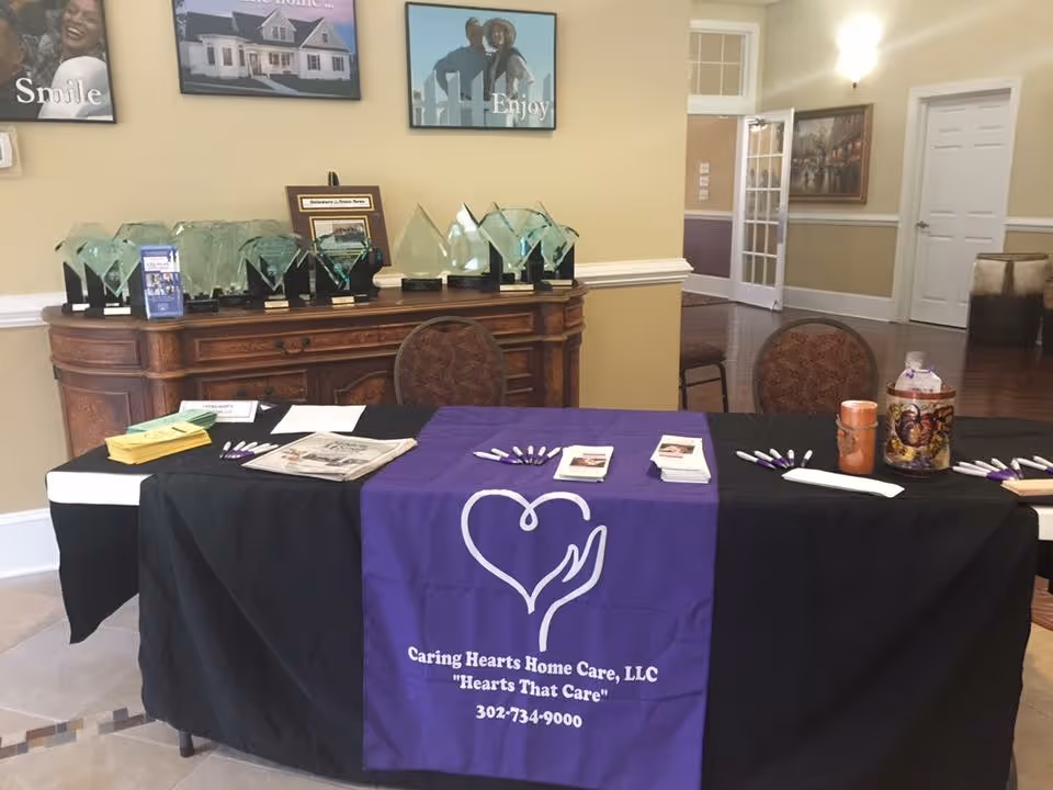 Reception table with purple Caring Hearts banner in a hallway of a senior care facility.