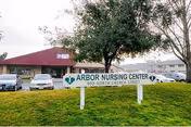 Exterior view of Arbor Rehabilitation & Nursing Center with sign, parking lot, and cars.