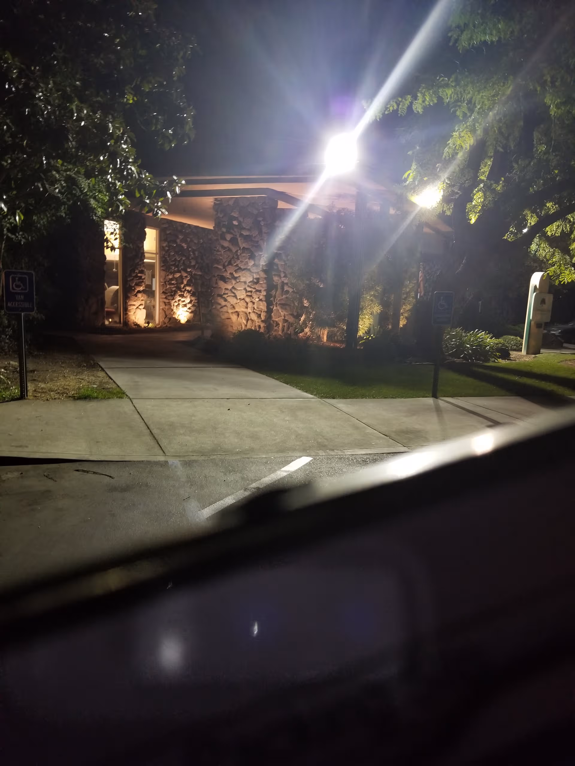 Nighttime exterior of Oakwood Gardens Care Center with stone entrance and illuminated walkway.