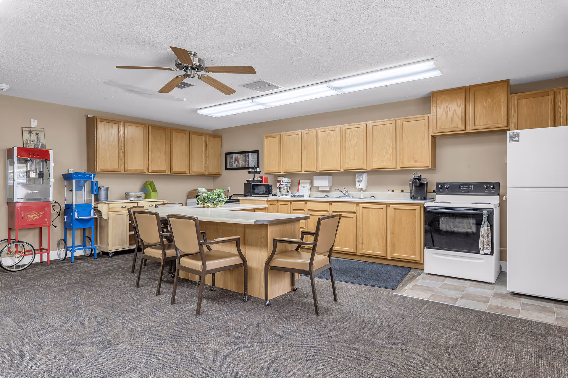 Interior kitchen area of a senior living facility with island, cabinets, and appliances.