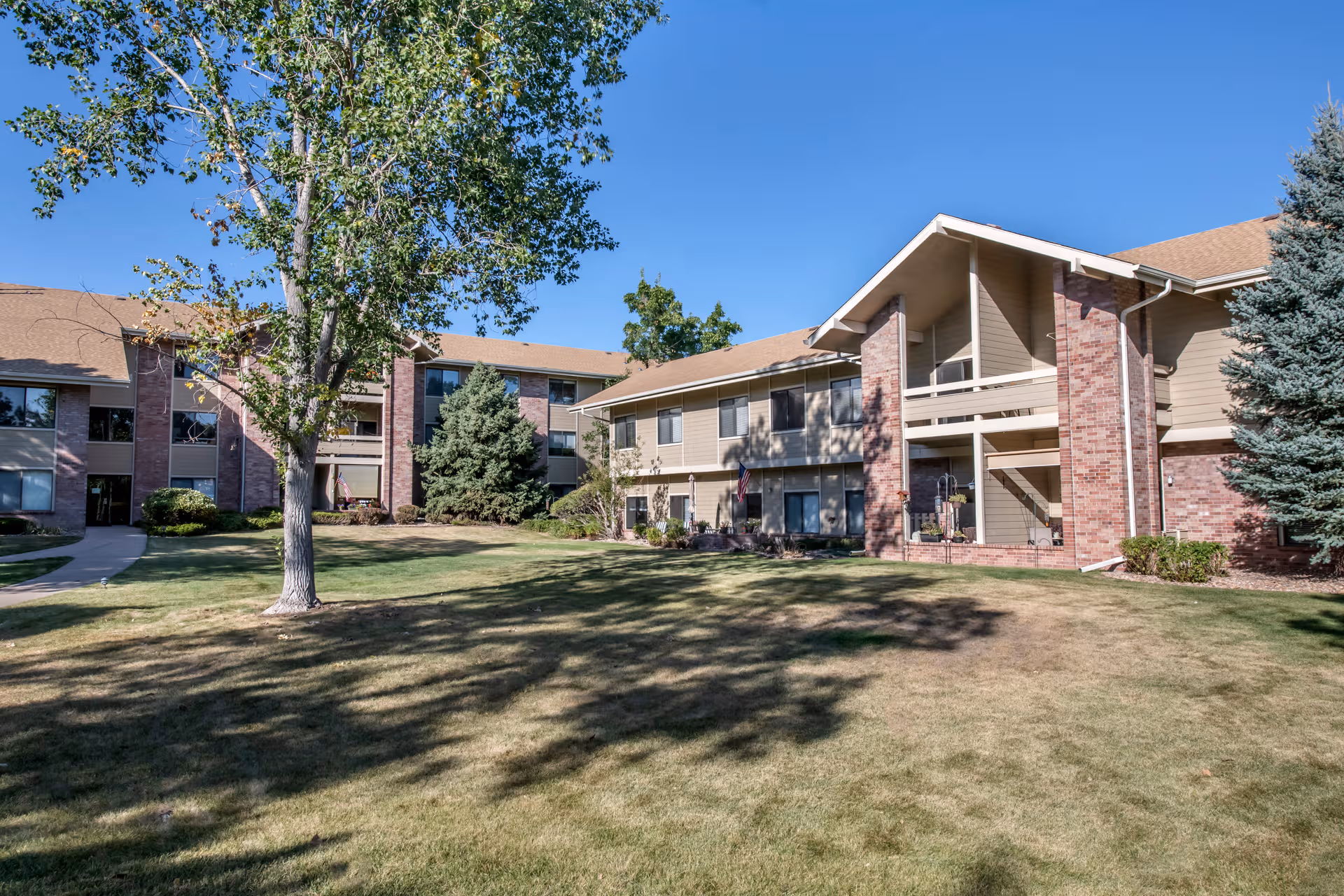 Exterior view of Brookdale Meridian Lakewood showing a brick residential building with a lawn and trees.
