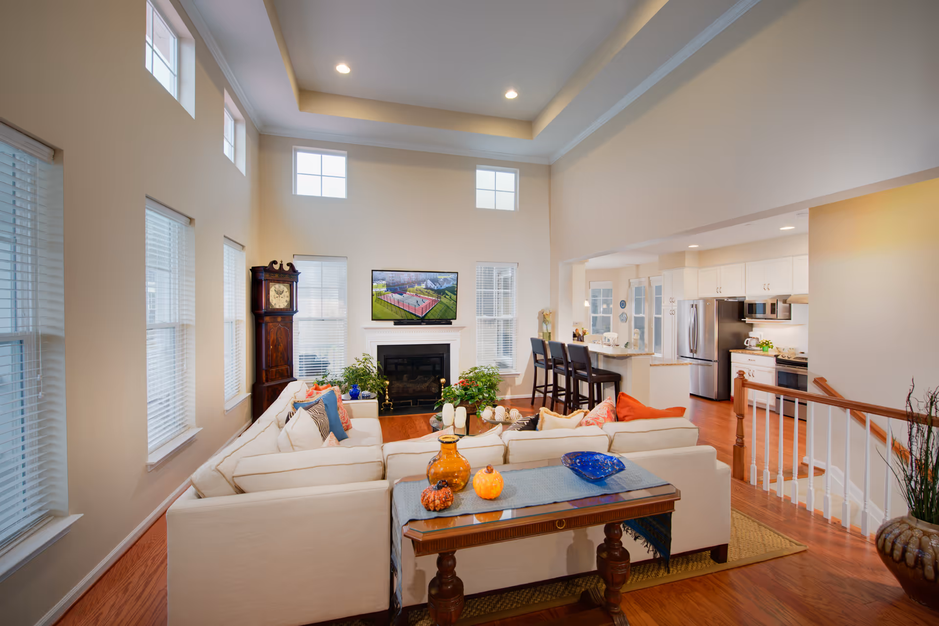 Spacious living room with cream sofas, fireplace, TV, and open kitchen in the background